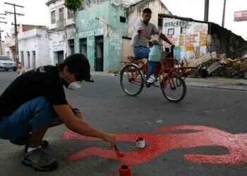 Um ativista pinta a silhueta de uma vítima de assassinato na favela do Coque, em Recife.