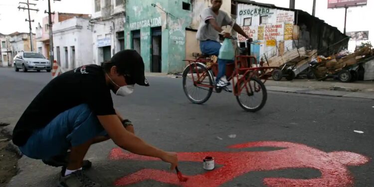 Um ativista pinta a silhueta de uma vítima de assassinato na favela do Coque, em Recife.