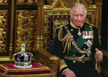 Charles III sentado ao lado da coroa da então rainha durante a abertura do Parlamento, no Palácio de Westminster, em 2022