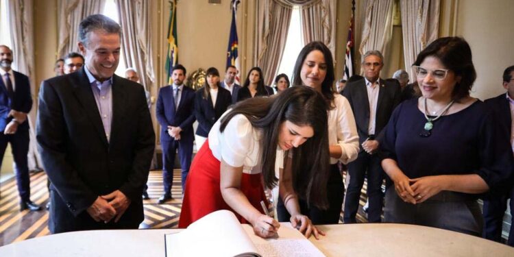 André "é todo sorriso" ao ver sua filha assinando o termo de posse