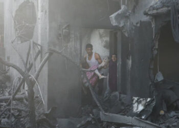 Um homem carrega uma menina palestina ferida no local dos ataques israelenses a uma casa, em Khan Younis, no sul da Faixa de Gaza.