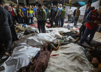 Pessoas ao redor de corpos de palestinos mortos em ataques de Israel ao hospital Ahli Arab, em Gaza.