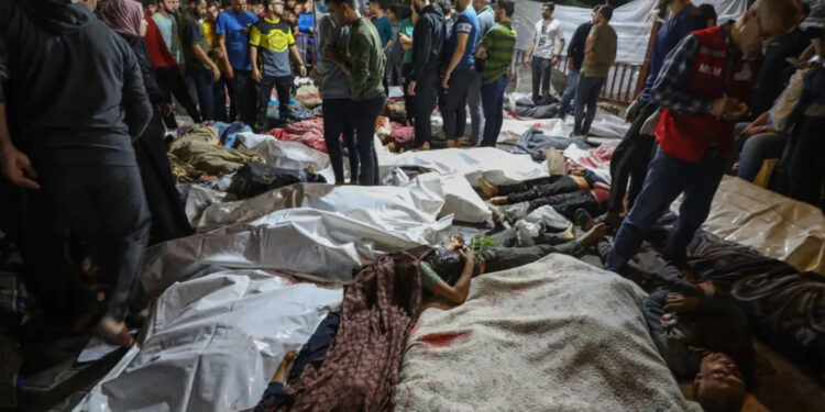 Pessoas ao redor de corpos de palestinos mortos em ataques de Israel ao hospital Ahli Arab, em Gaza.