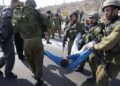 Soldados israelenses carregam um palestino ferido em briga durante um protesto na estrada 443, perto da aldeia de Beit Ur, na Cisjordânia