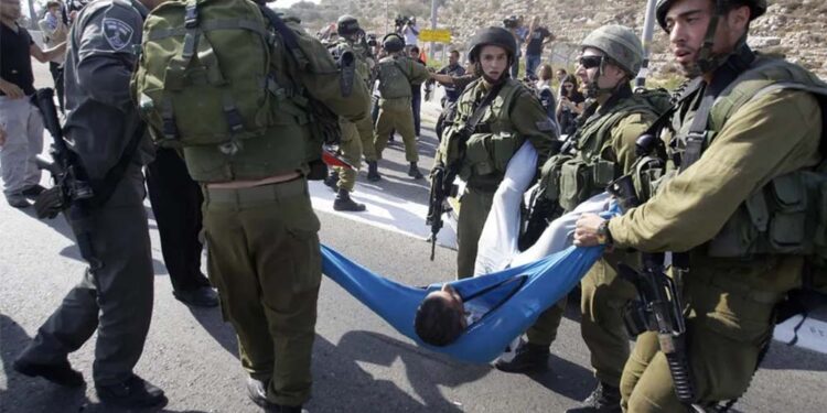 Soldados israelenses carregam um palestino ferido em briga durante um protesto na estrada 443, perto da aldeia de Beit Ur, na Cisjordânia