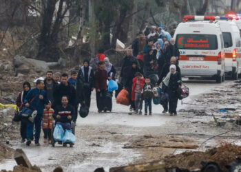 Pessoas caminham entre casas destruídas pelos ataques israelenses, em meio a uma trégua temporária entre Israel e Hamas, na cidade de Gaza.