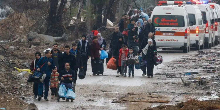 Pessoas caminham entre casas destruídas pelos ataques israelenses, em meio a uma trégua temporária entre Israel e Hamas, na cidade de Gaza.