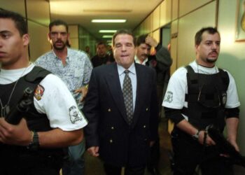 O poderoso banqueiro paulista do jogo do bicho escoltado por policiais civis do GOE, em junho de 1996.