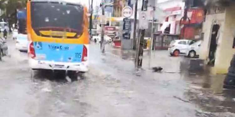 Ônibus passar por avenida alagada no Recife