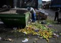 Homem procura alimentos em conteiner de descarte no Mercado Central da Argentina, em Buenos Aires,
