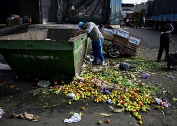 Homem procura alimentos em conteiner de descarte no Mercado Central da Argentina, em Buenos Aires,
