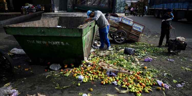 Homem procura alimentos em conteiner de descarte no Mercado Central da Argentina, em Buenos Aires,