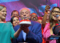 Lula apaga as velas do bolo do PT enquanto Janja canta "parabéns".