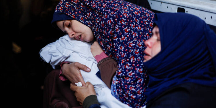 Rania Abu Anza, mãe dos gêmeos Wesam e Naeem Abu Anza, mortos em Rafah, abraça os corpos dos filhos