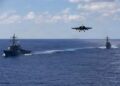F-18 se aproxima do USS Gerald Ford com Mahan e Bainbridge ao fundo