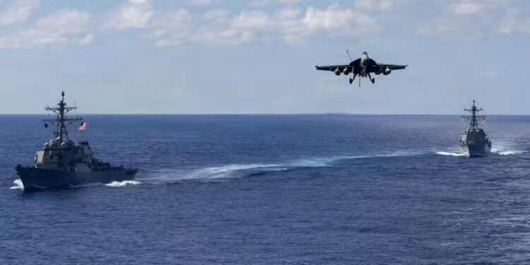 F-18 se aproxima do USS Gerald Ford com Mahan e Bainbridge ao fundo