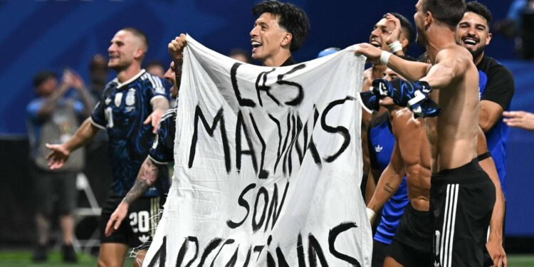 Jogadores argentinos com a faixa escrito 'As Malvinas são argentinas" no gramado